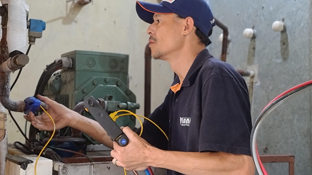 Image of a technician in uniform working with wires and machinery within a building.
